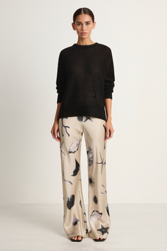Woman wearing a black sweater and patterned pants on a white background