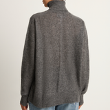 Person wearing a gray sweater and blue jeans on a plain background
