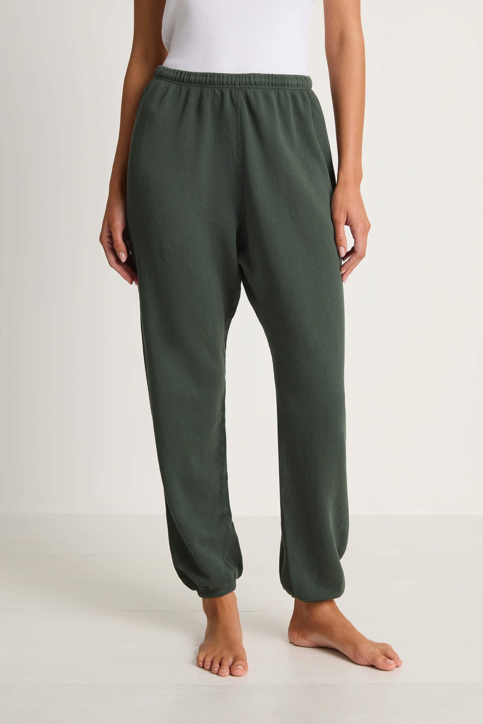 Person wearing green lounge pants on a white background