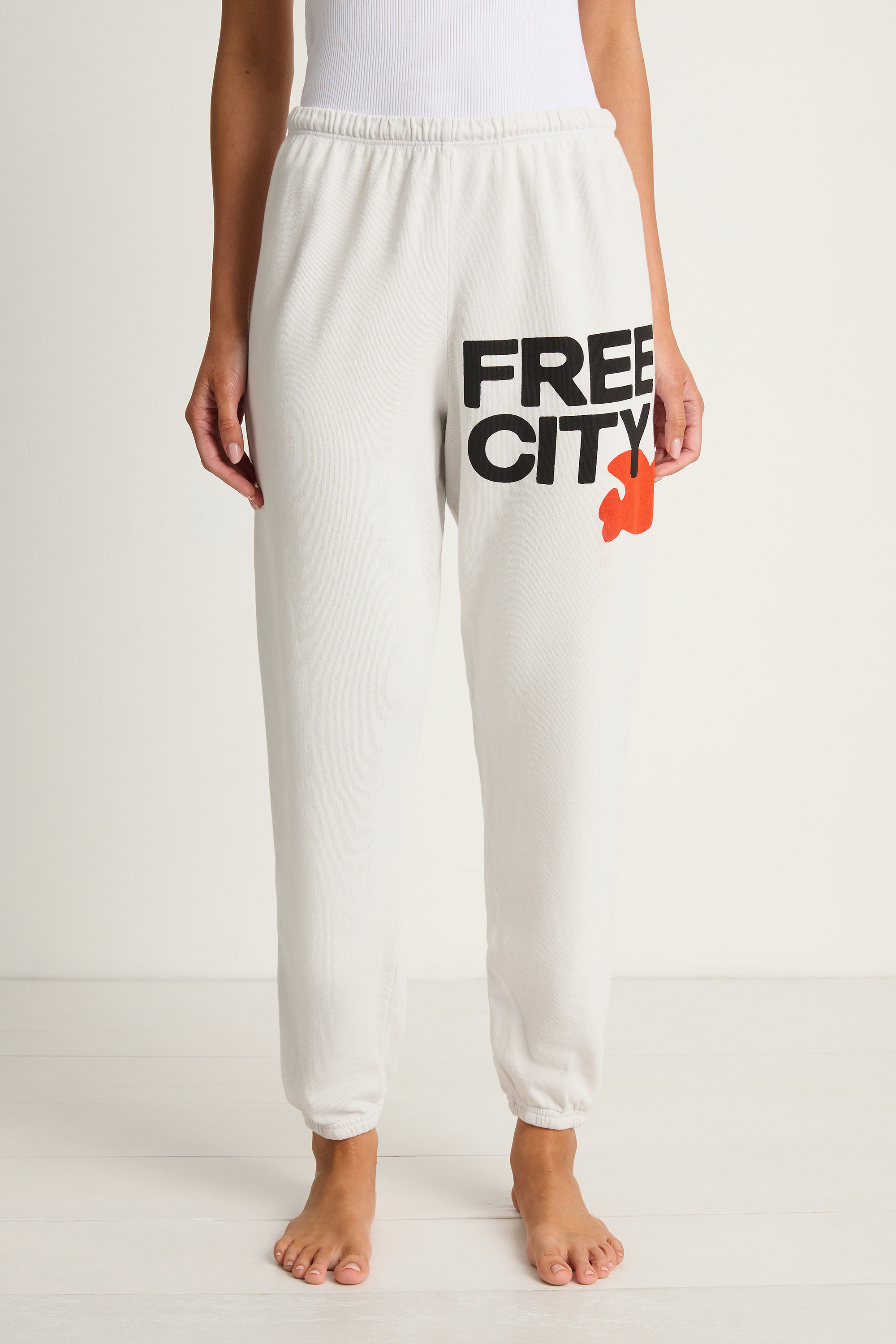 White sweatpants with 'FREE CITY' text and logo on a white background