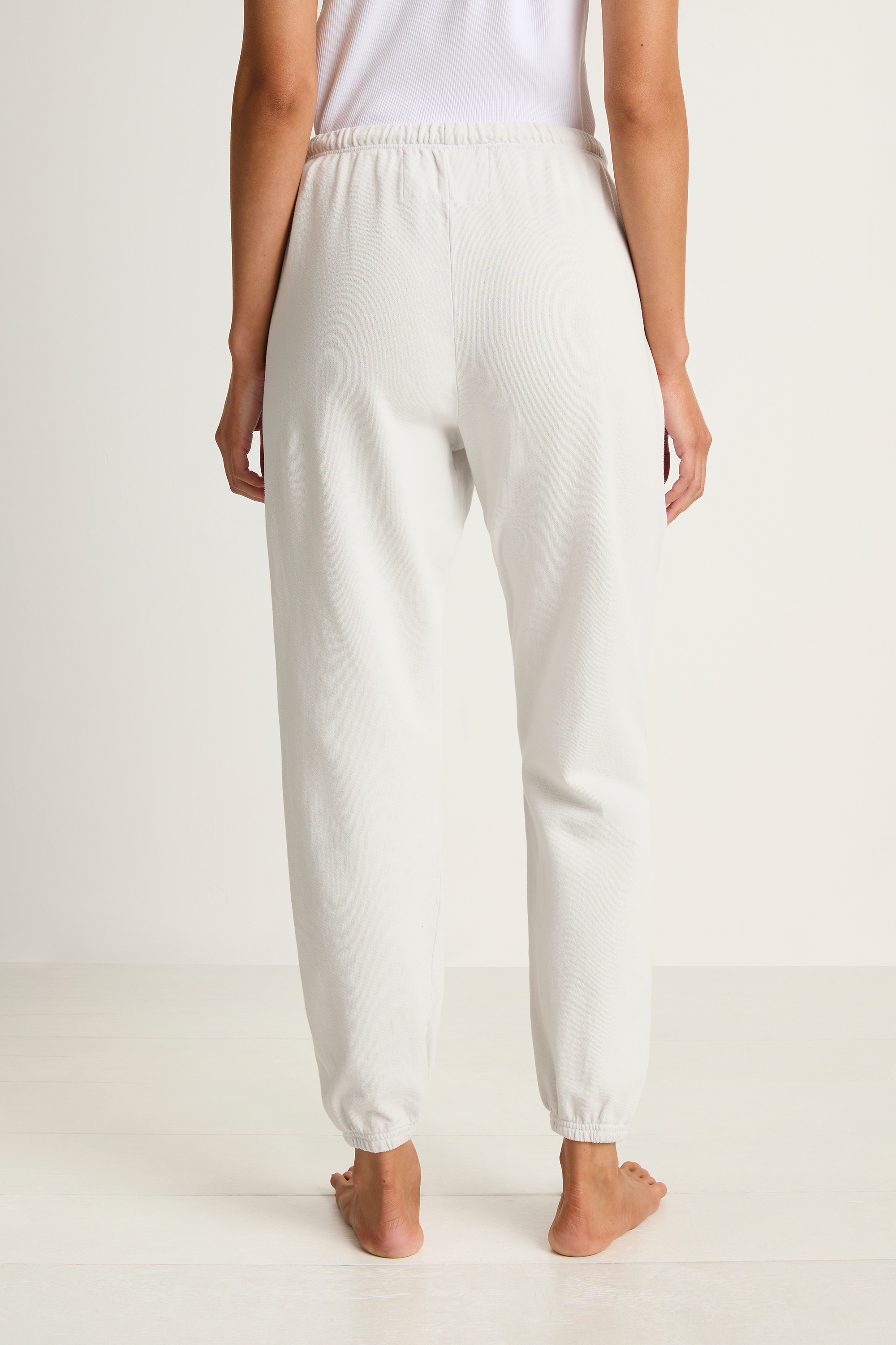White sweatpants worn by a person on a white background