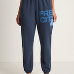 Navy sweatpants with 'FREECITY' logo worn by a person on a white background