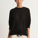 Woman wearing a black sweater with a plain background