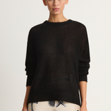 Woman wearing a black sweater with a plain background