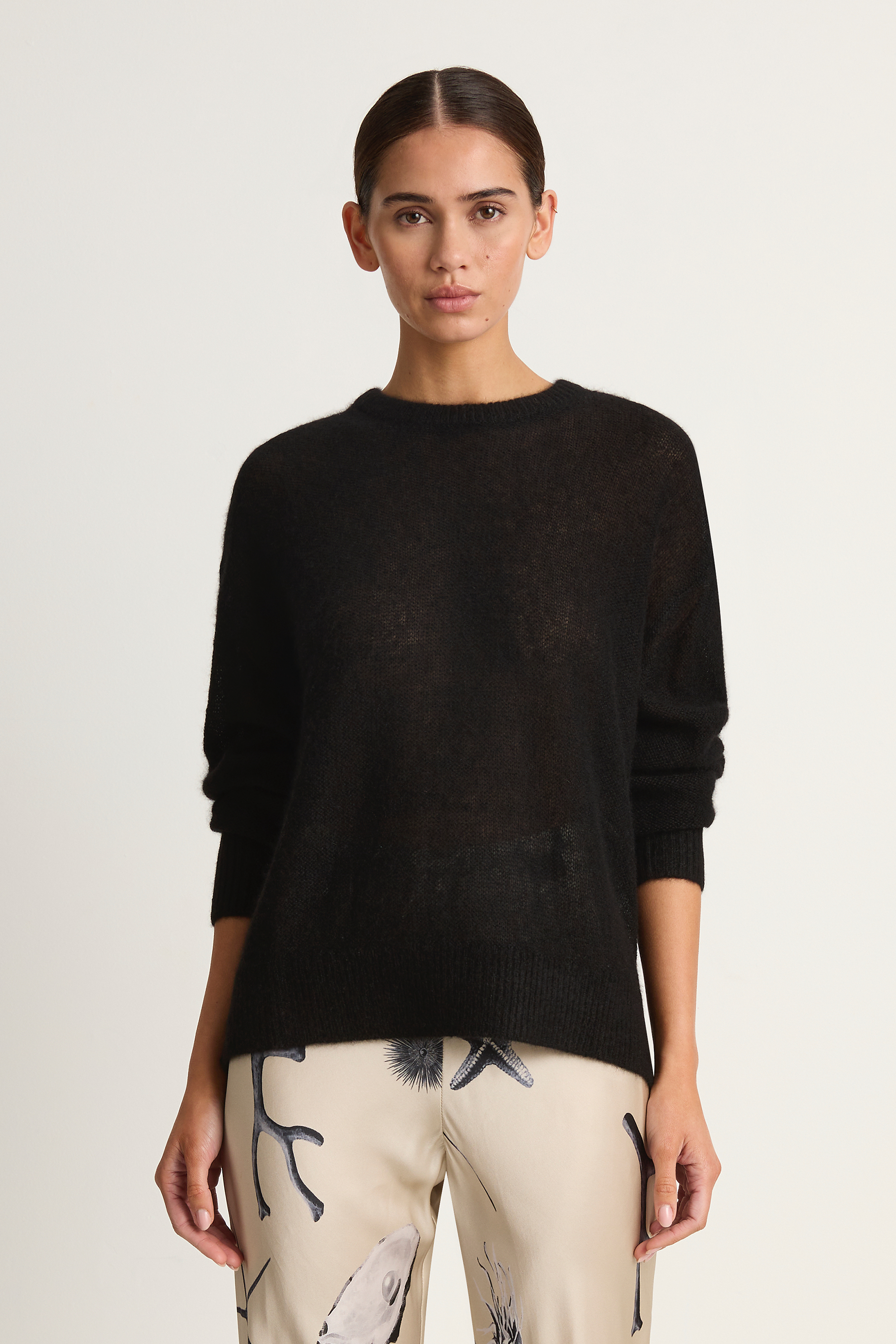 Woman wearing a black sweater with a plain background