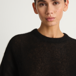 Woman wearing a black sweater against a plain background
