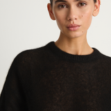 Woman wearing a black sweater against a plain background