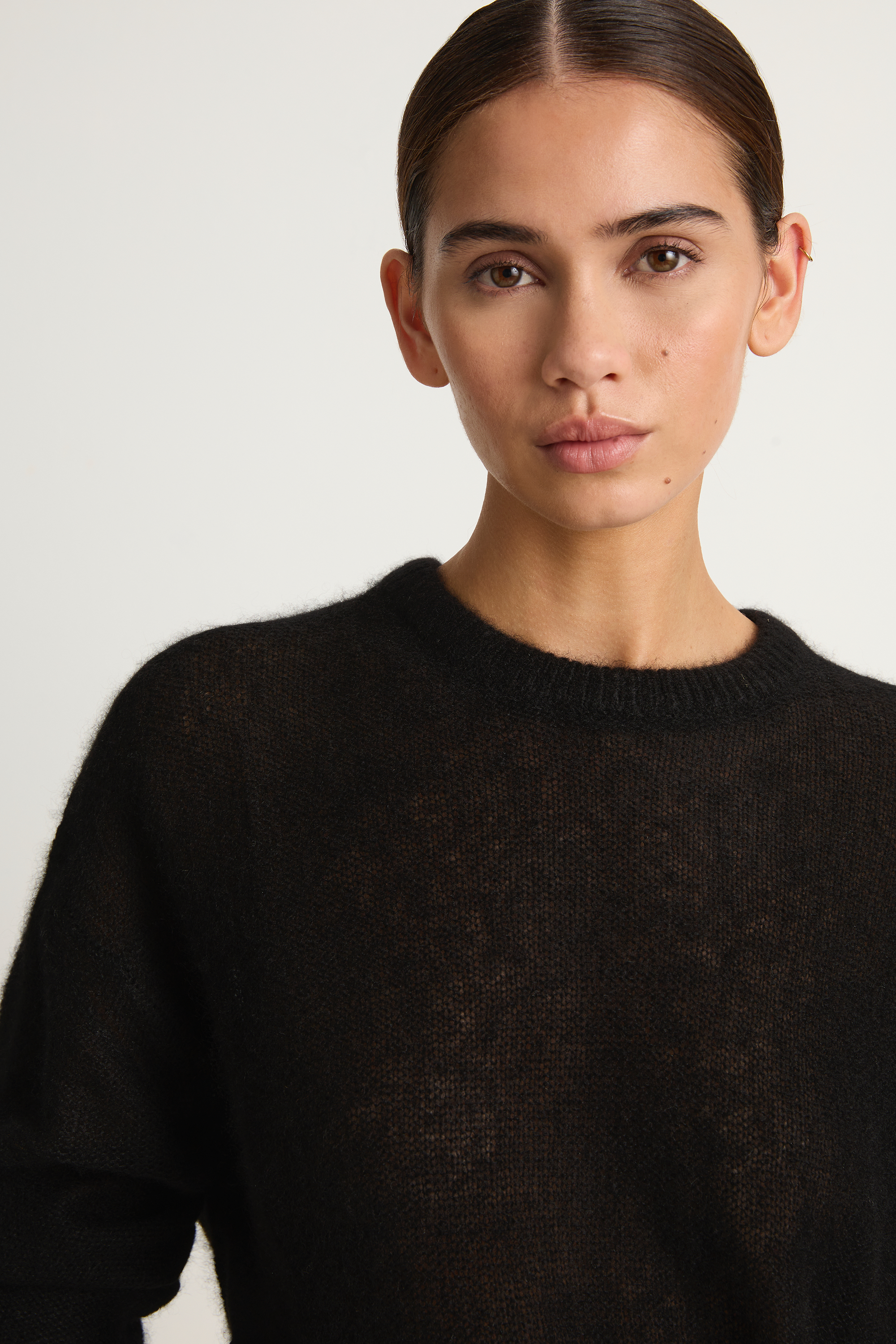 Woman wearing a black sweater against a plain background