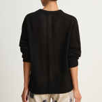 Person wearing a black sweater with patterned pants on a white background
