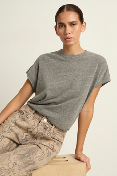 Woman wearing a gray t-shirt and patterned pants on a neutral background