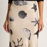 Beige skirt with black sea-themed pattern worn by a person against a white background