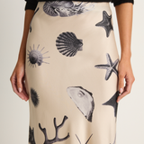 Beige skirt with black sea-themed pattern worn by a person against a white background