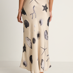 Person wearing a beige skirt with black sea creature prints on a plain background