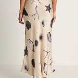 Person wearing a beige skirt with black sea creature prints on a plain background