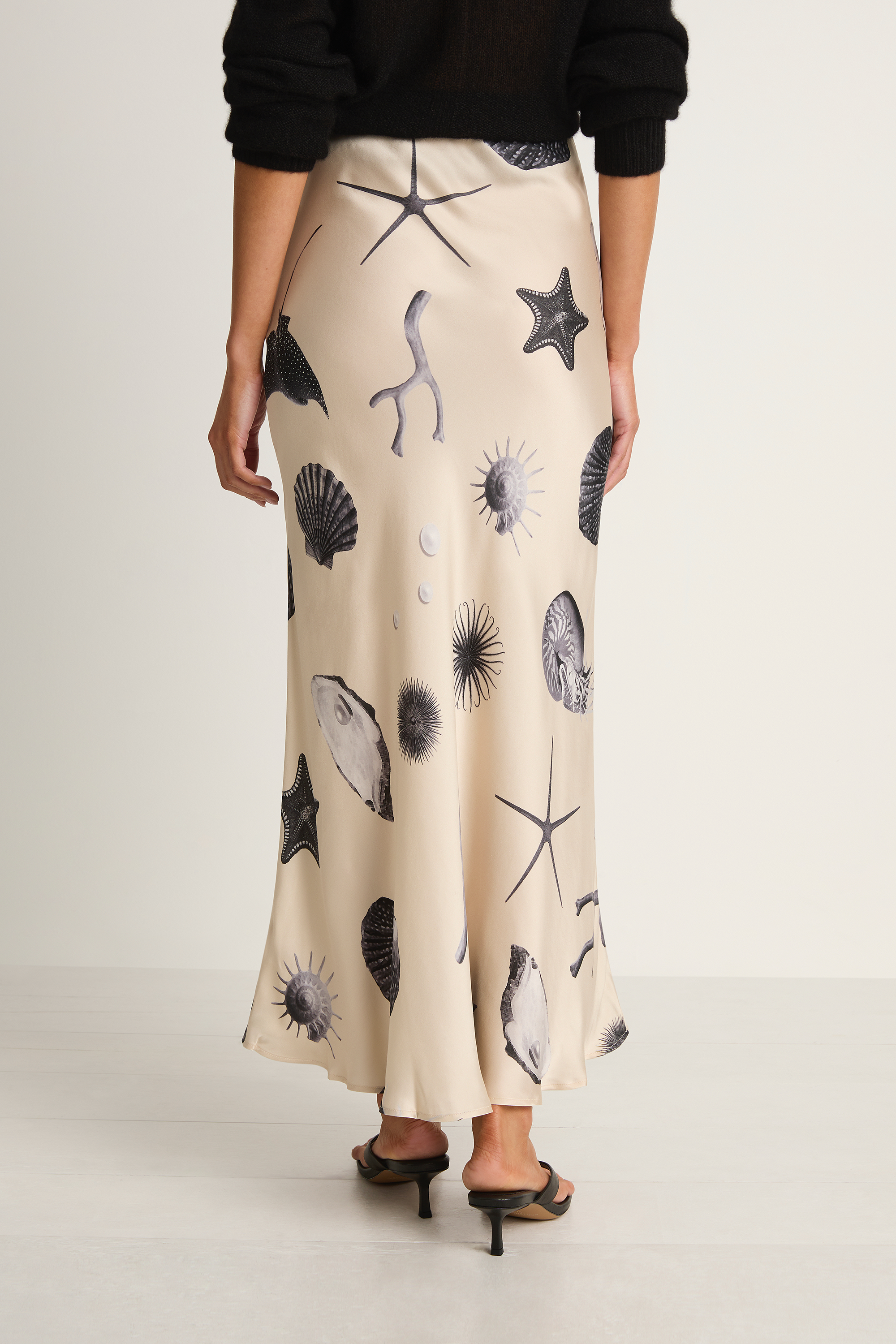 Person wearing a beige skirt with black sea creature prints on a plain background