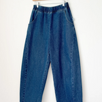 Blue jeans hanging on a wooden hanger against a white background