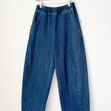 Blue jeans hanging on a wooden hanger against a white background