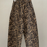 Leopard print pants hanging on a wooden hanger against a plain background
