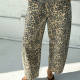 Person wearing leopard print pants and a green top on a light-colored floor.