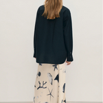 Woman wearing a black shirt and patterned skirt against a white background