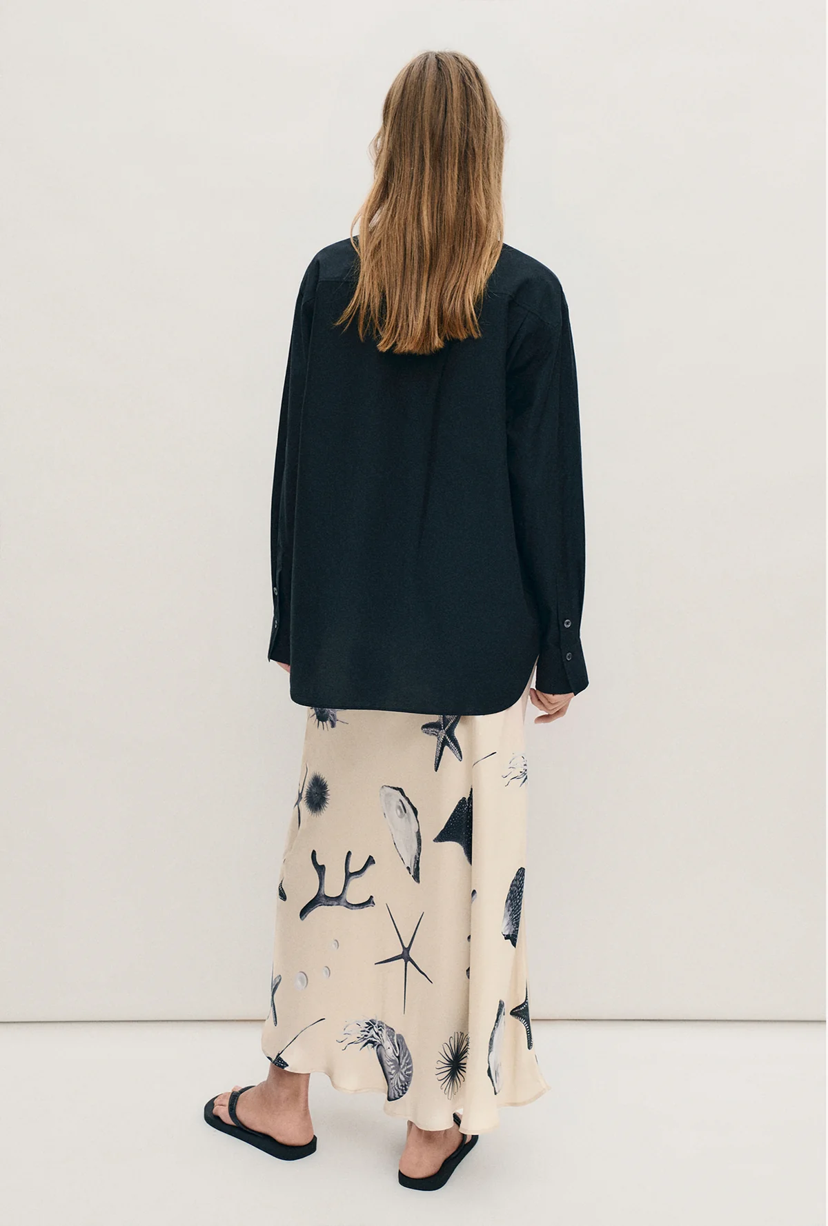 Woman wearing a black shirt and patterned skirt against a white background