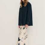 Woman wearing a black shirt and patterned pants against a white background