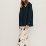 Woman wearing a black shirt and patterned pants against a white background