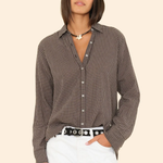 Woman wearing a checkered shirt and white pants on a beige background