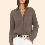 Woman wearing a checkered shirt and white pants on a beige background
