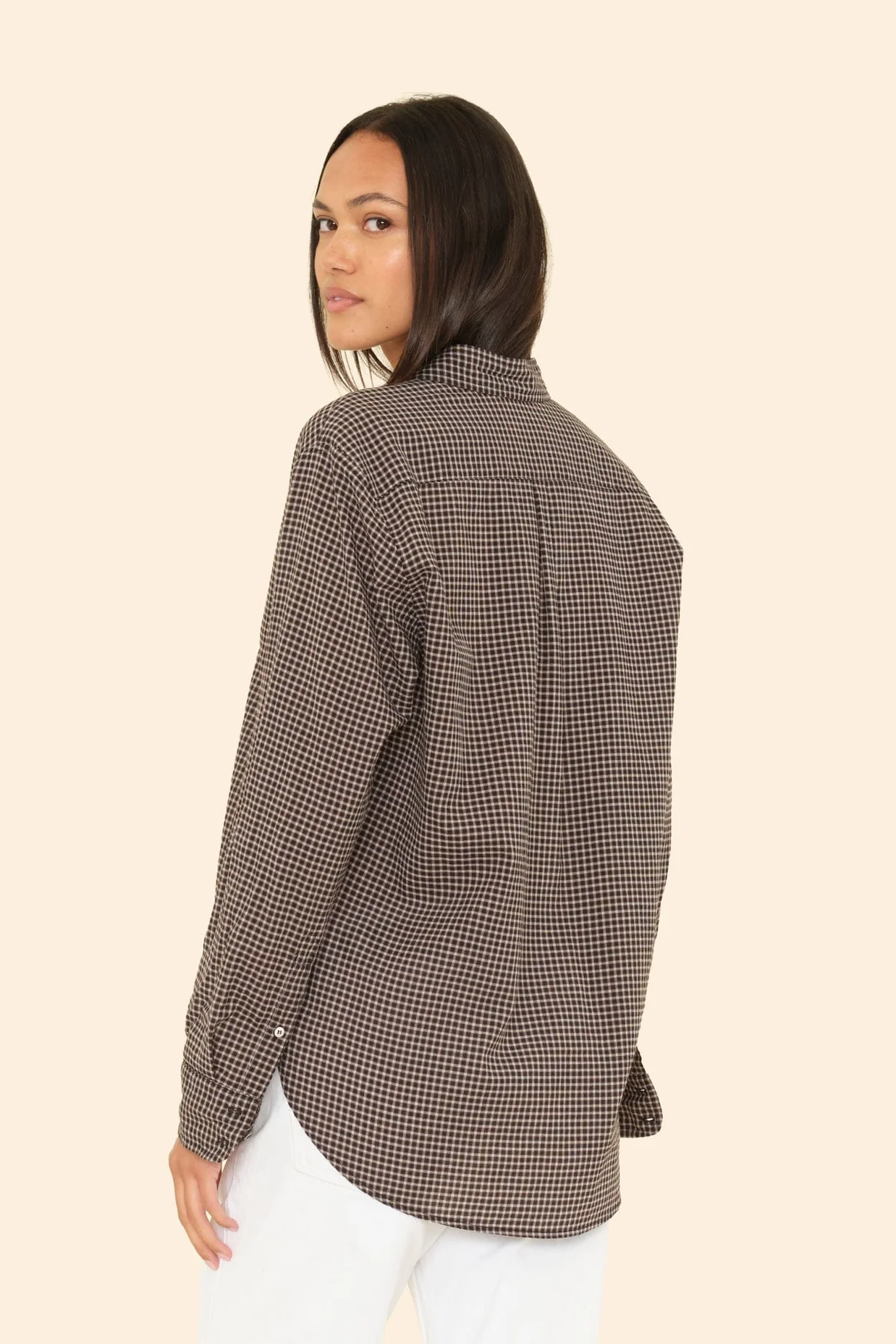 Woman wearing a checkered shirt on a beige background