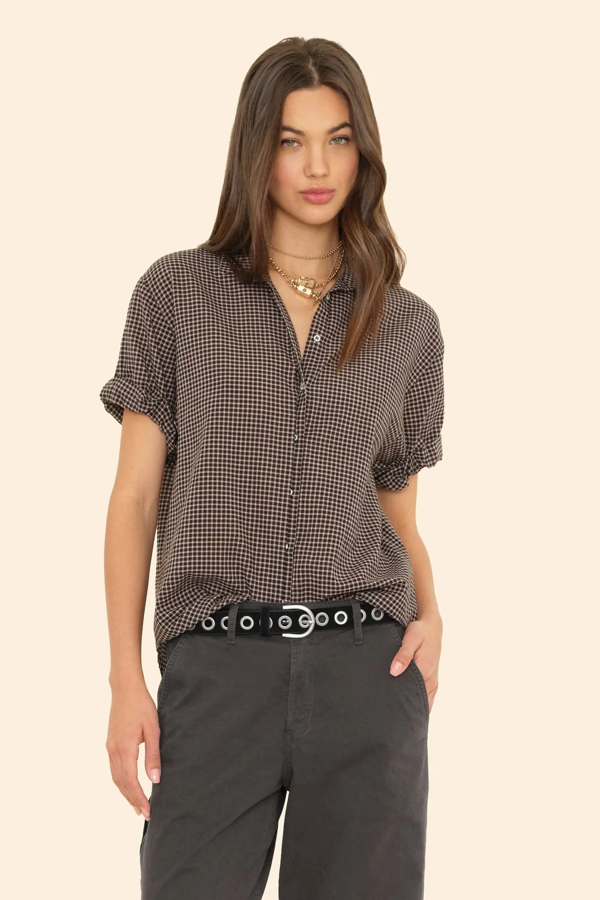 Woman wearing a patterned blouse and dark pants on a beige background