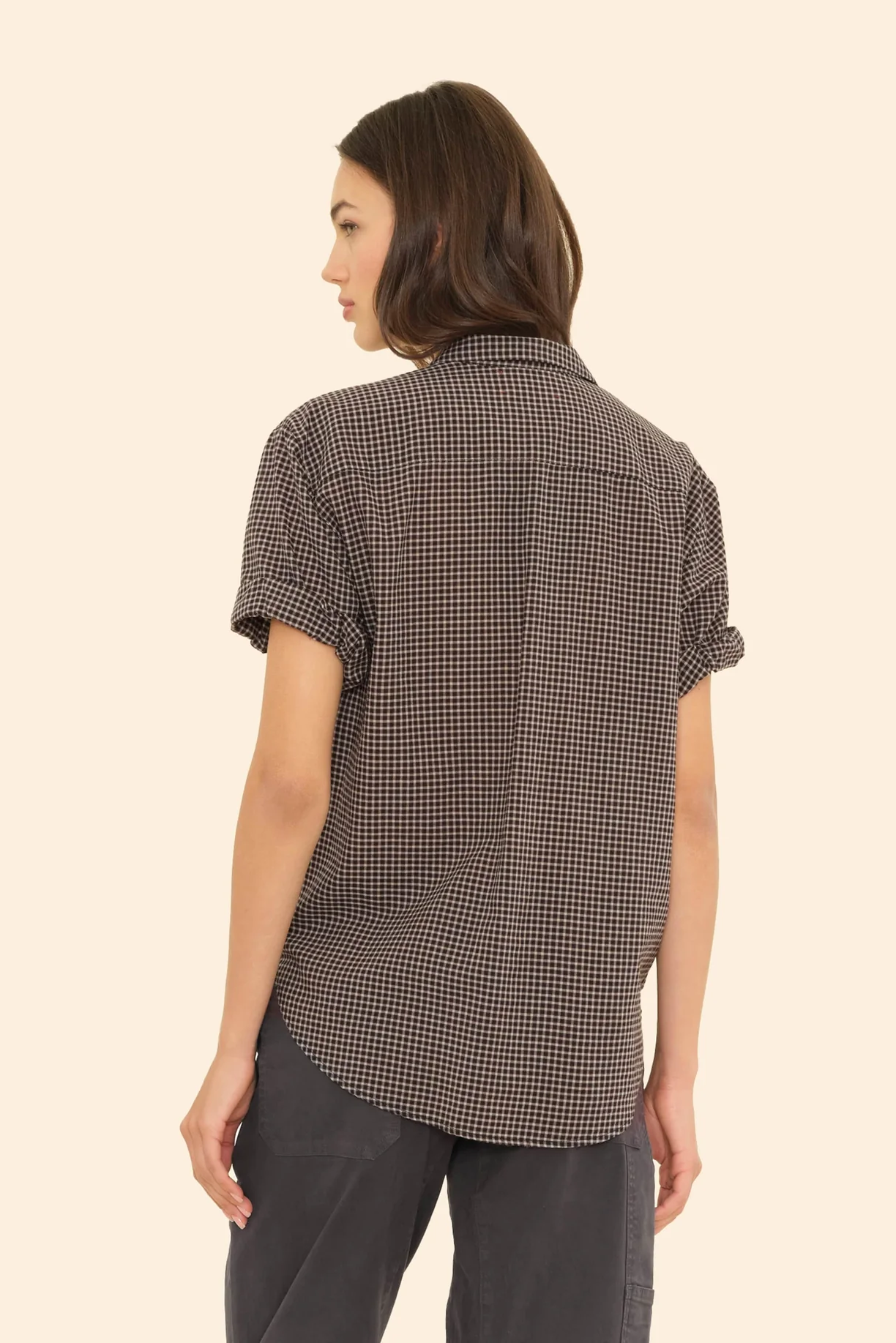 Woman wearing a checkered shirt on a beige background
