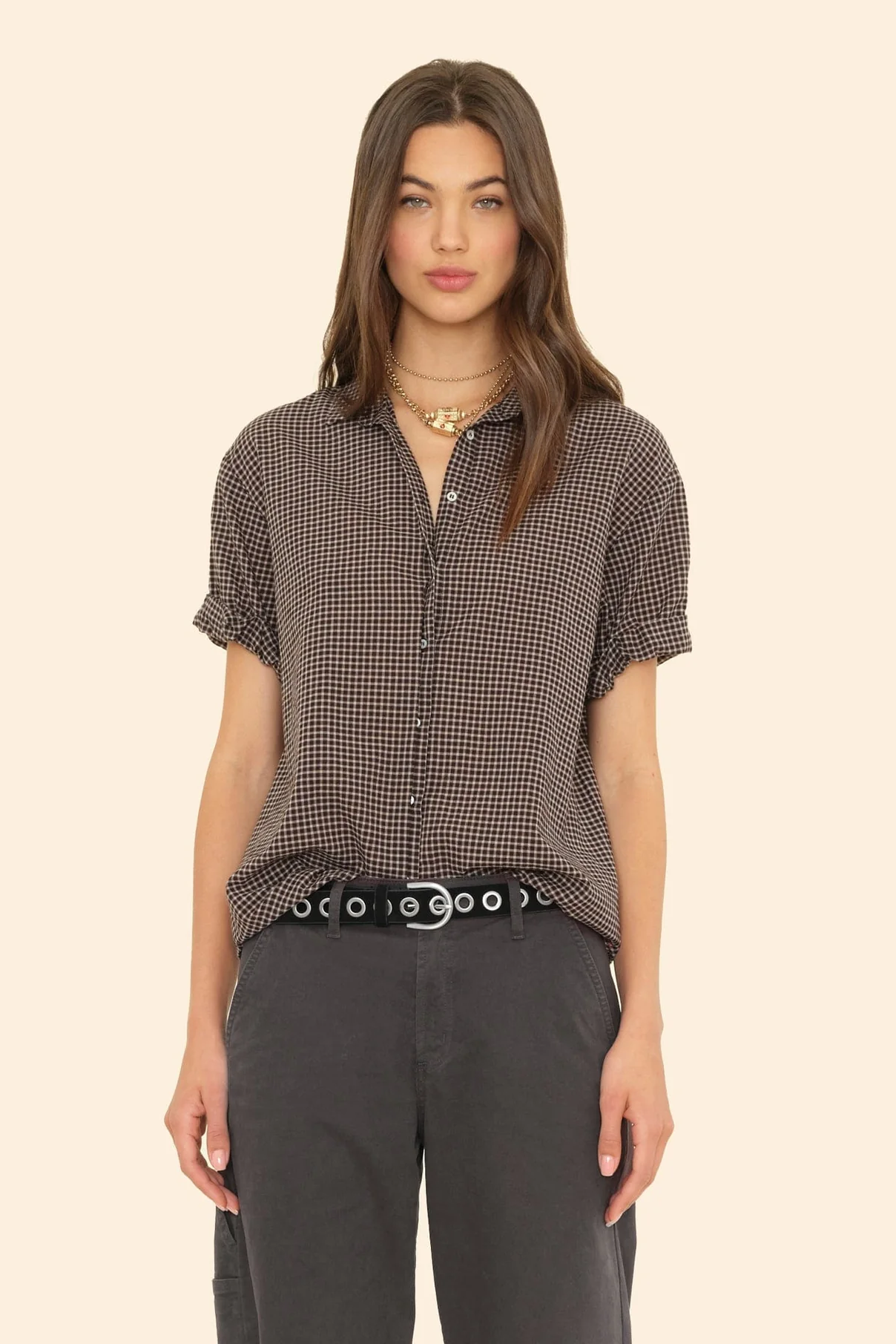 Woman wearing a checkered shirt and dark pants on a beige background